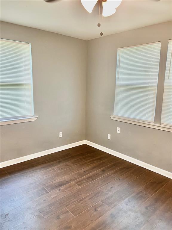 unfurnished room with ceiling fan and dark wood-type flooring