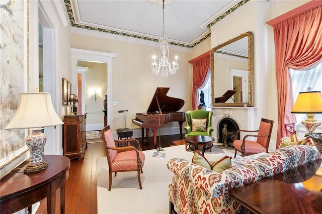 living area with crown molding, an inviting chandelier, and hardwood / wood-style flooring