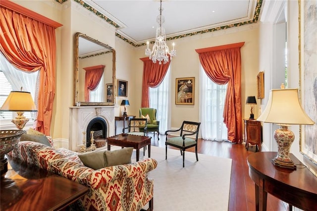 living area featuring dark hardwood / wood-style flooring, ornamental molding, and an inviting chandelier