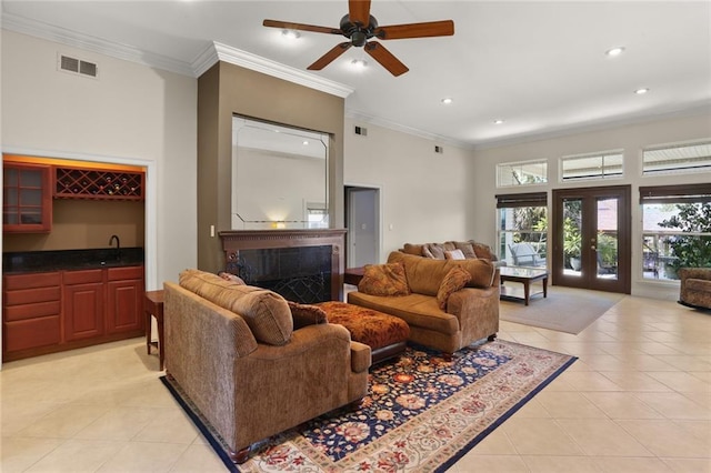 tiled living room featuring ornamental molding, ceiling fan, french doors, and indoor wet bar