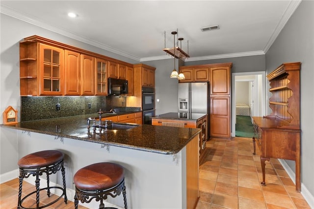 kitchen featuring pendant lighting, ornamental molding, kitchen peninsula, black appliances, and dark stone counters