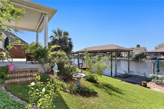 view of yard featuring a dock, a water view, and a patio area