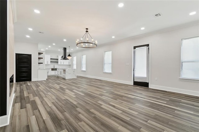 unfurnished living room with a chandelier, light hardwood / wood-style flooring, and sink