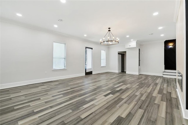 unfurnished living room with crown molding, wood-type flooring, and a notable chandelier