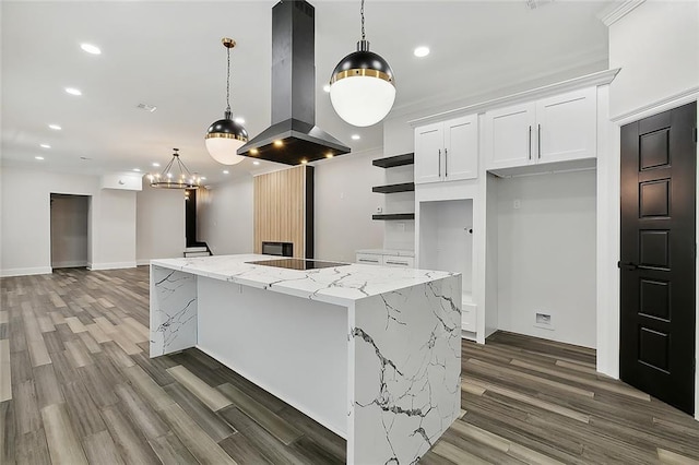 kitchen with light stone countertops, island range hood, pendant lighting, white cabinetry, and a large island