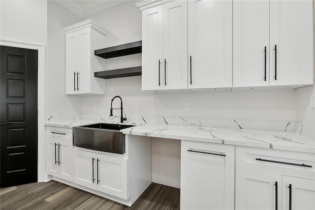 kitchen with light stone countertops, white cabinetry, dark wood-type flooring, and sink