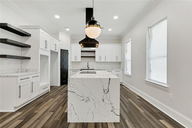 kitchen featuring white cabinets, decorative light fixtures, a center island, and light stone countertops