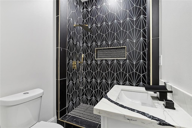 bathroom with tiled shower, vanity, and toilet