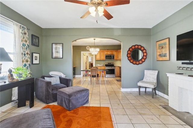 tiled living room with ceiling fan with notable chandelier