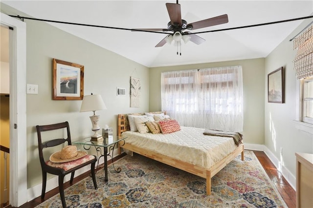 bedroom with ceiling fan, vaulted ceiling, and dark hardwood / wood-style flooring