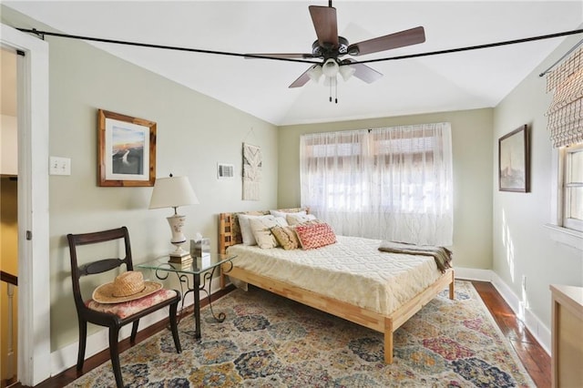 bedroom featuring lofted ceiling, visible vents, a ceiling fan, baseboards, and dark wood-style flooring