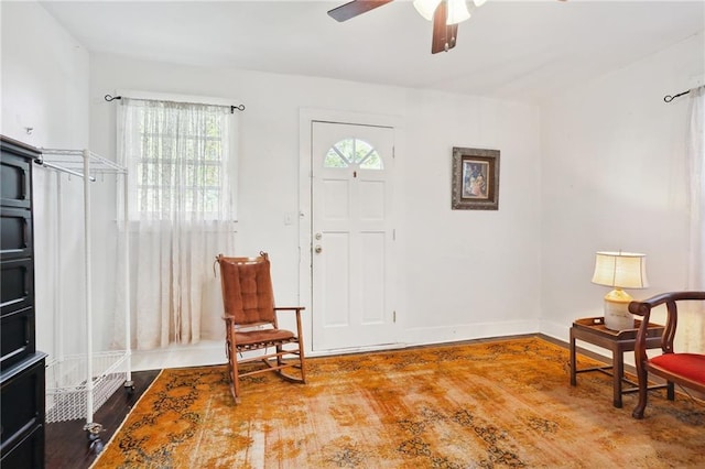 sitting room with ceiling fan, baseboards, and wood finished floors
