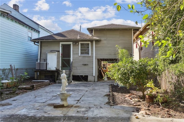 rear view of house featuring cooling unit, fence, a patio, and a shingled roof