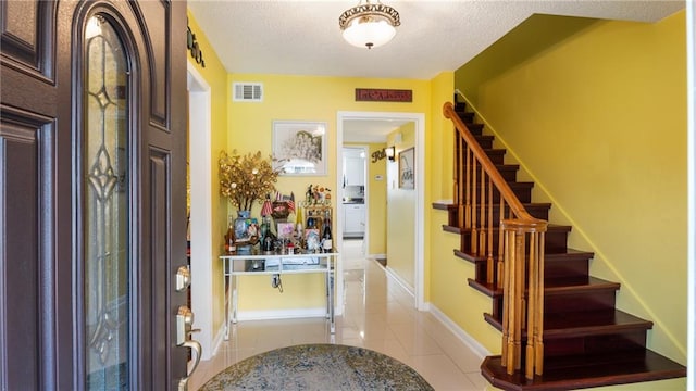 foyer featuring light tile patterned floors and a textured ceiling