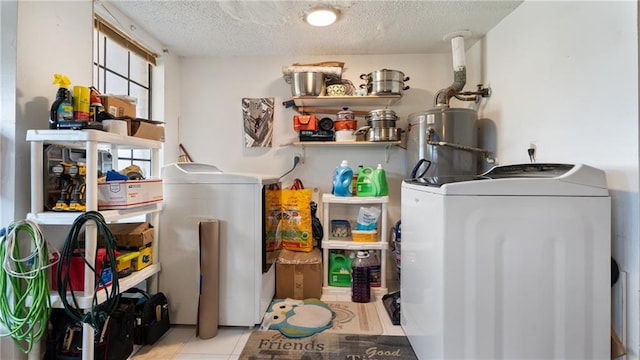 clothes washing area featuring separate washer and dryer, water heater, and a textured ceiling