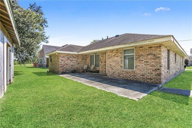 170 Becs Pl, Braithwaite, LA 70040 - back of house featuring a patio, a yard, a shingled roof, and brick siding