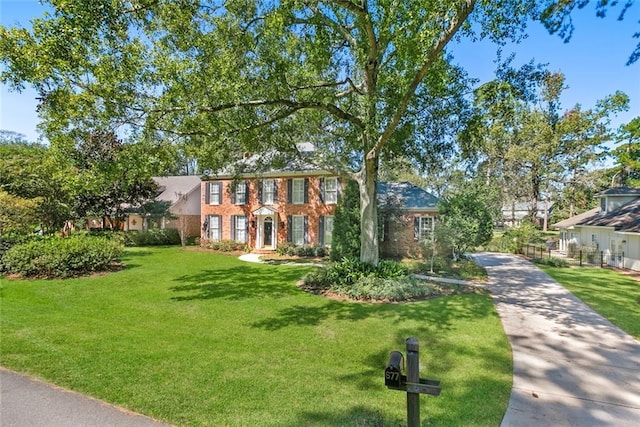 colonial-style house with brick siding, a front lawn, and driveway