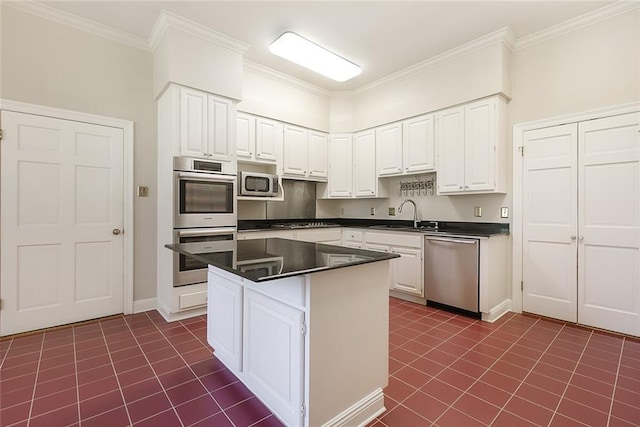 kitchen with dark countertops, ornamental molding, dark tile patterned floors, appliances with stainless steel finishes, and white cabinetry