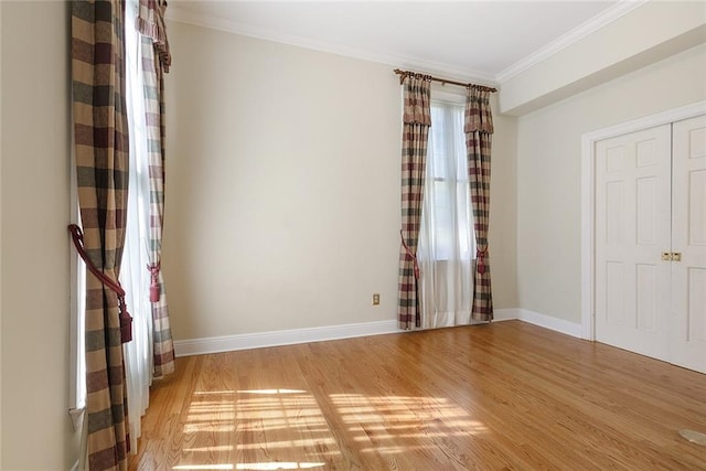 unfurnished room featuring light wood-type flooring, crown molding, and baseboards