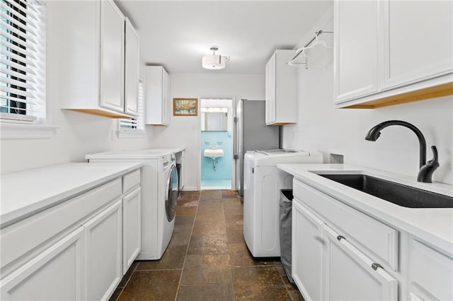 washroom with cabinets, sink, and independent washer and dryer