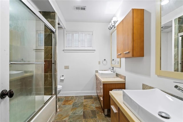 full bathroom with bath / shower combo with glass door, vanity, and toilet