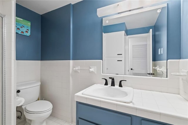 bathroom with tile patterned flooring, vanity, tile walls, and toilet