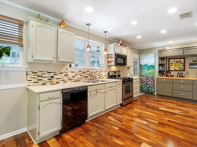 kitchen with hanging light fixtures, light hardwood / wood-style floors, black appliances, and a wealth of natural light