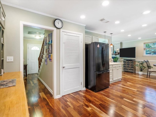 kitchen with pendant lighting, ornamental molding, black refrigerator, white cabinetry, and light hardwood / wood-style floors