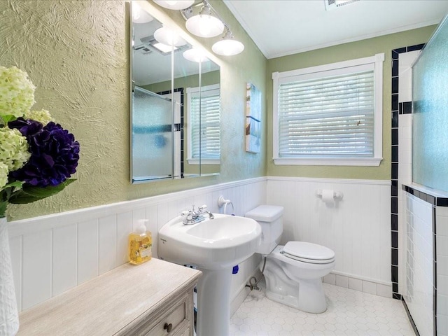 bathroom featuring tile patterned flooring, ornamental molding, a shower with shower door, and toilet