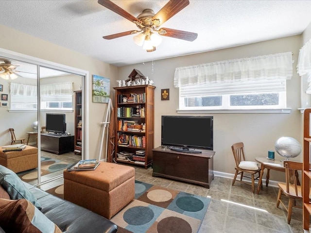 641 Adair St, Mandeville, LA 70448 - living room featuring a ceiling fan, healthy amount of natural light, a textured ceiling, and baseboards
