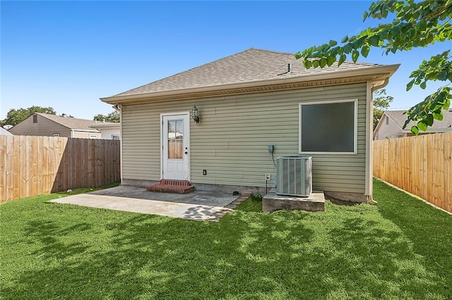 back of property with a lawn, a patio area, and central AC