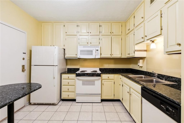 kitchen featuring dark stone countertops, light tile patterned flooring, sink, and white appliances