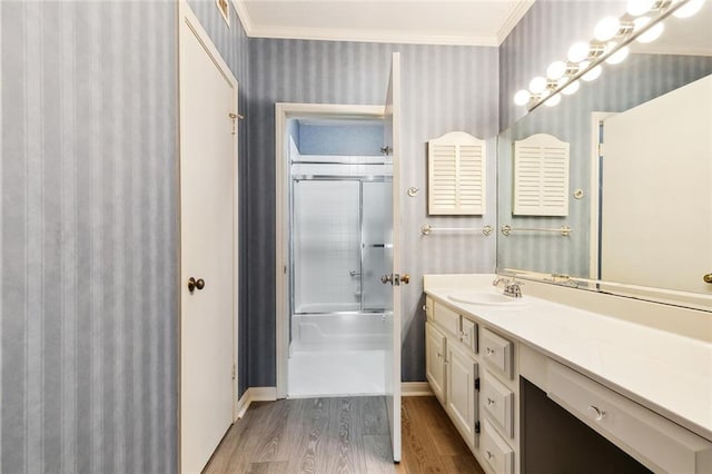 bathroom featuring shower / bath combination with glass door, vanity, ornamental molding, and hardwood / wood-style flooring