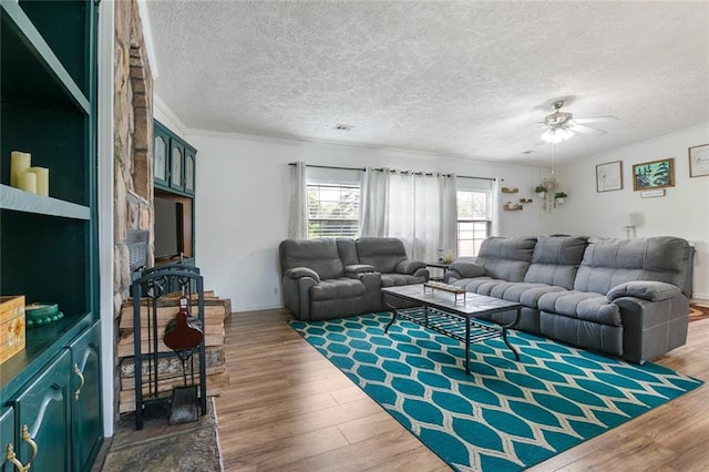 living room with ornamental molding, hardwood / wood-style flooring, ceiling fan, and a textured ceiling