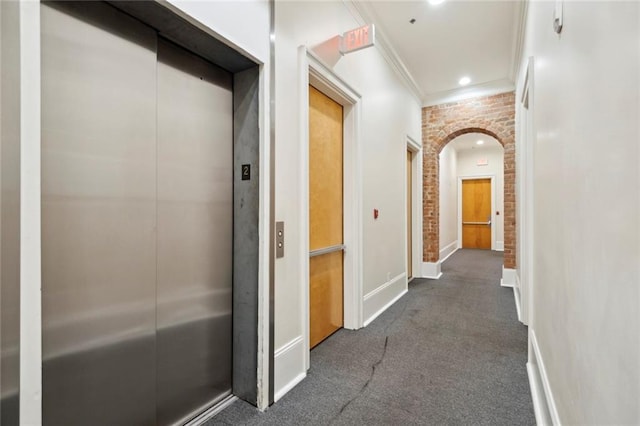 hall with ornamental molding, brick wall, and elevator