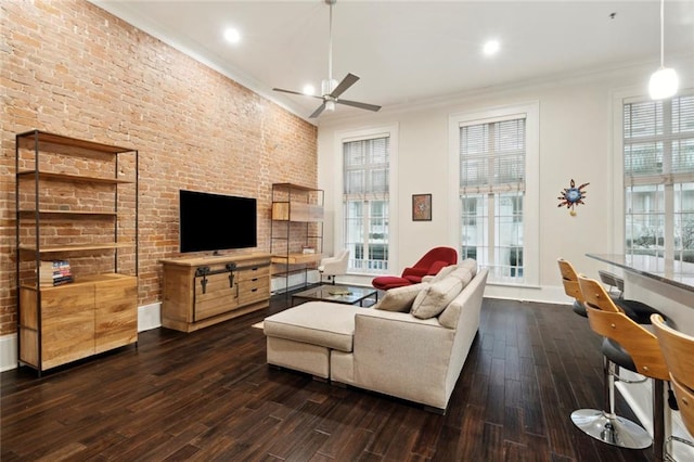 living room featuring ornamental molding, ceiling fan, dark hardwood / wood-style floors, and brick wall