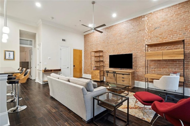 living room with ornamental molding, ceiling fan, dark hardwood / wood-style floors, and brick wall