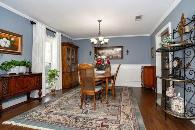 dining area featuring dark wood finished floors, a notable chandelier, crown molding, and visible vents