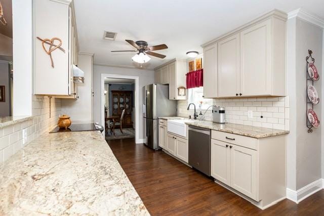 kitchen featuring light stone counters, visible vents, appliances with stainless steel finishes, dark wood-type flooring, and ceiling fan