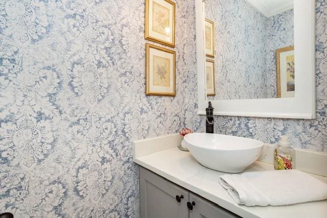 bathroom featuring crown molding, vanity, and wallpapered walls