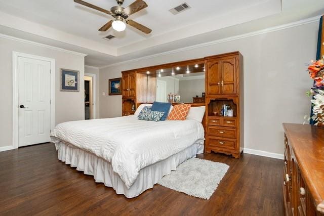 bedroom featuring a tray ceiling, dark wood-style flooring, visible vents, and baseboards