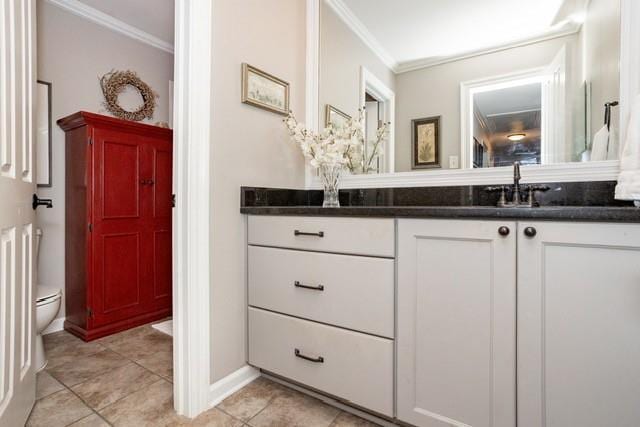 bathroom featuring crown molding, toilet, vanity, baseboards, and tile patterned floors