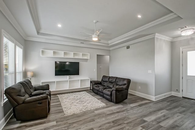 living room featuring hardwood / wood-style flooring, crown molding, ceiling fan, and a raised ceiling