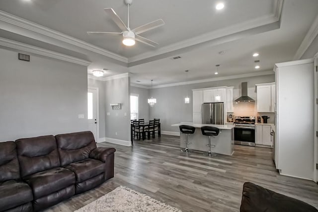 living room featuring ceiling fan with notable chandelier, ornamental molding, and light hardwood / wood-style flooring