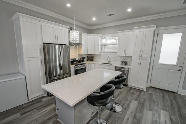 kitchen with a center island, white cabinets, sink, pendant lighting, and appliances with stainless steel finishes