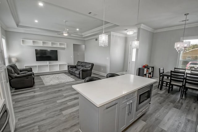 kitchen featuring hanging light fixtures, stainless steel microwave, hardwood / wood-style flooring, and a kitchen island