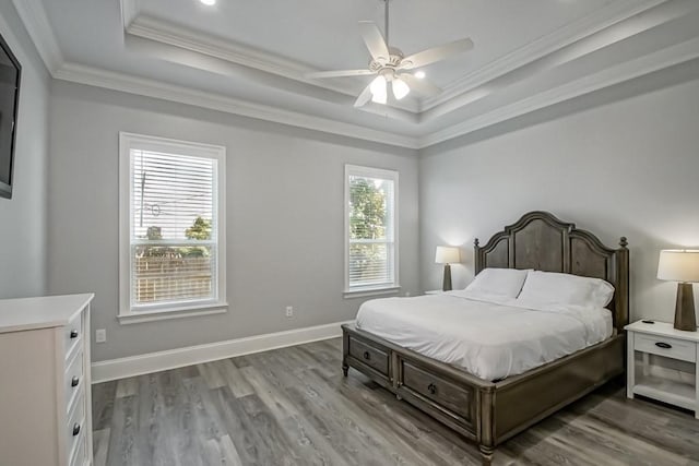 bedroom featuring hardwood / wood-style flooring, crown molding, ceiling fan, and a raised ceiling