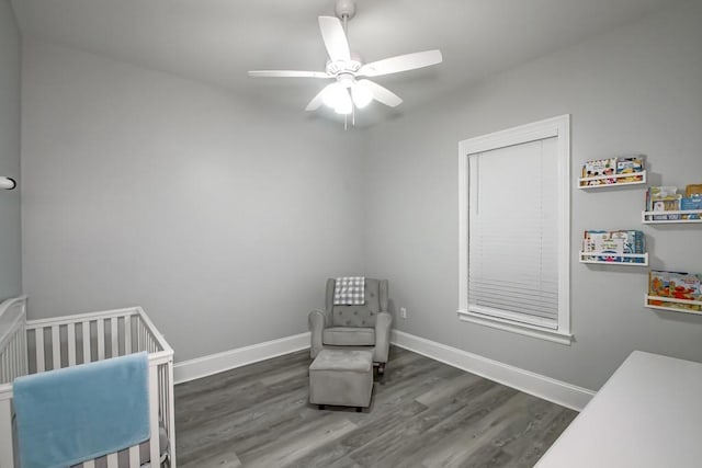 bedroom featuring ceiling fan, a crib, and dark hardwood / wood-style flooring