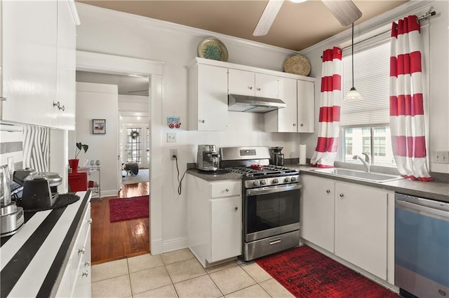 kitchen featuring appliances with stainless steel finishes, light tile patterned flooring, sink, white cabinets, and ornamental molding