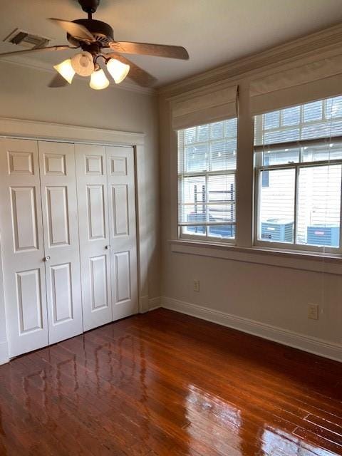 unfurnished bedroom with dark hardwood / wood-style flooring, crown molding, a closet, and ceiling fan